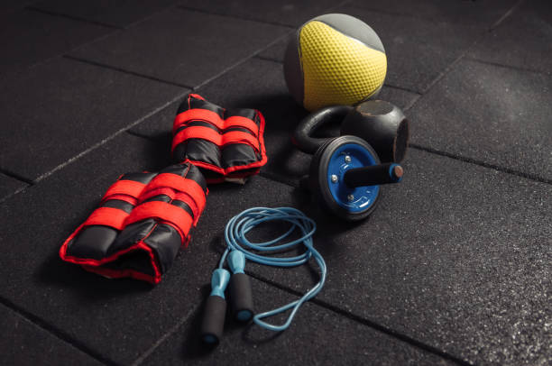 istock Functional training equipment. Kettlebell and skipping rope, ab roller, medicine ball, massage roller, weights on a dark black floor. Bodybuilding and fitness 1279522778
