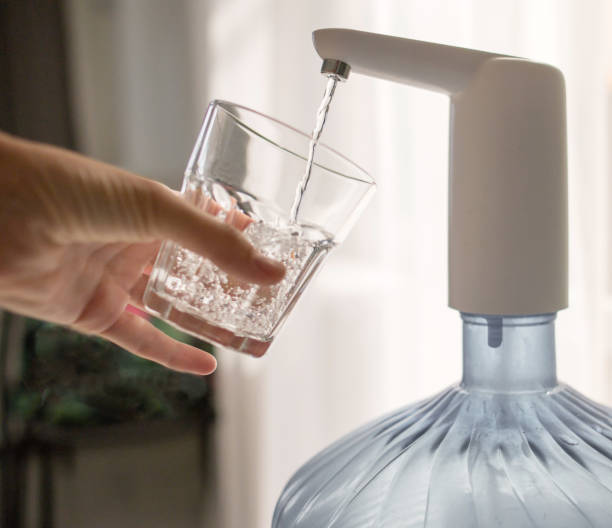 istock hand with a glass pours water from the cooler 1279522780