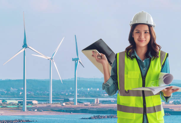 istock Female Civil engineer with computer and blueprint is standing infront on wind turbine for Sustainable energy industry development concept. 1279524722