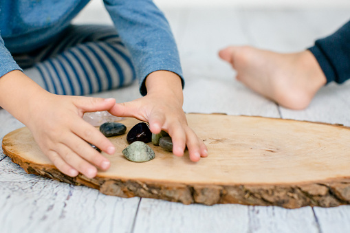 Children playing with stones (crystals) on a wooden board
