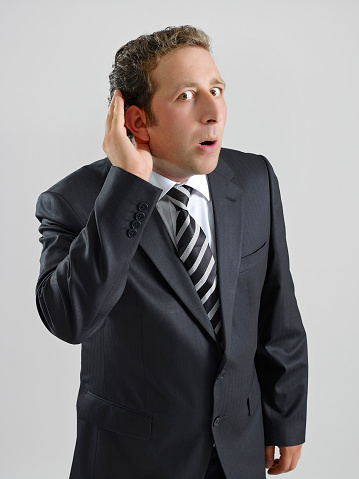Businessman making a gesture as if e is trying to hear