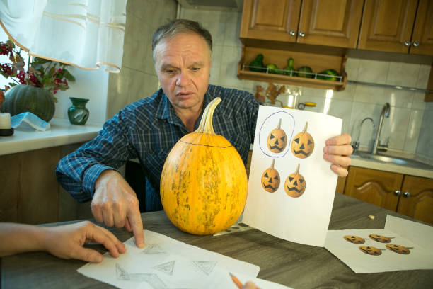 making jack o'lantern at home. jack o'lantern thread template creation process. the man prepares the pumpkin for carving. - n64 imagens e fotografias de stock