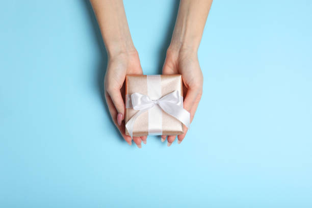 istock gift in female hands on a colored background top view. 1279533614