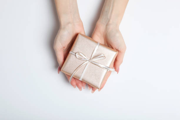 istock gift in female hands on a colored background top view. 1279533618