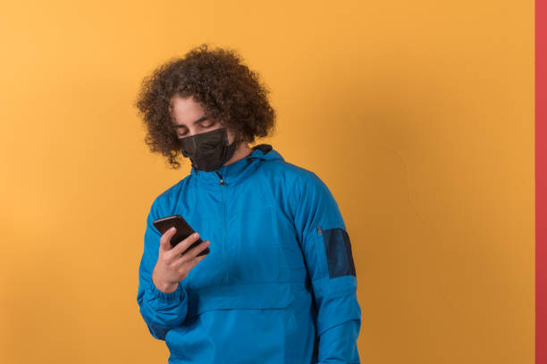 istock Young man wearing protective face mask and using phone. 1279533883
