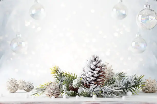 Photo of Christmas still life with snowy pine cones, baubles and  fir branches on light background.