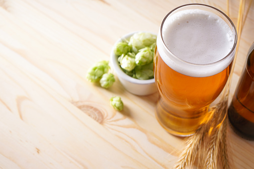 Hops and light beer on wooden background, space for text