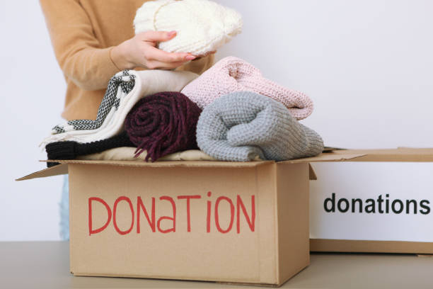istock girl puts in a box with donations items. Volunteering 1279536190