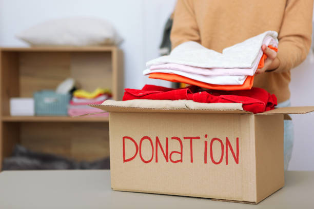 istock girl puts in a box with donations items. Volunteering 1279536319