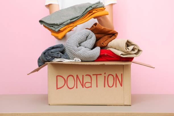 istock girl puts in a box with donations items. Volunteering 1279536324