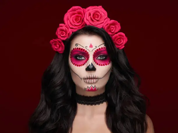 Portrait of a woman with sugar skull makeup over red background. Halloween costume and make-up. Portrait of Calavera Catrina