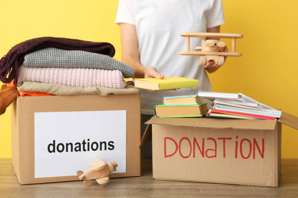 istock girl puts in a box with donations items. Volunteering 1279537164