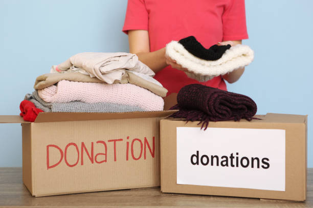istock girl puts in a box with donations items. Volunteering 1279537446