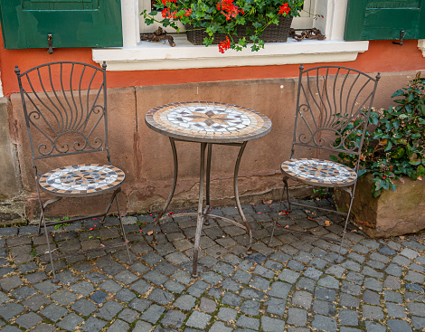 Two old mosaic chairs and a round mosaic table in front of the house