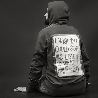 Adult man sits on a table wearing a hoodie that carries a message: \