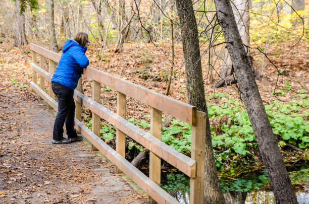 istock Woman on a small bridge looking at river in forest 1279554249