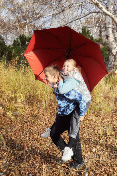istock Boy rolls a girl with an umbrella on his back 1279557661