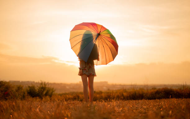 istock Anonymous woman with umbrella dreaming during sunset 1279564479
