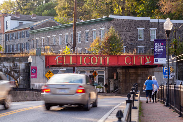 Welcome to Ellicott City sign written in large capital letters on side of the B&O railroad bridge at the entrance of city Ellicott City, MD, USA 10/07/2020: Welcome to Ellicott City sign written in large capital letters on side of the B&O railroad bridge at the entrance of city. Old houses and cars passing by are seen. ellicott city maryland stock pictures, royalty-free photos & images