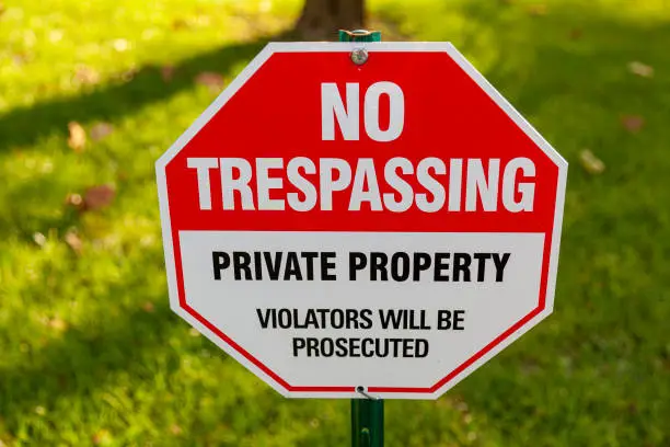 Close up isolated image of a metal red and white octagonal  warning yard sign that says "Private Property, "No Trespassing" "Violators will be prosecuted" There is copy space on sides for text.