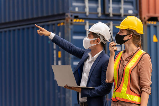 inspetor ou empresário conversando com trabalhador das docas e laptop usado verificando contêiner de carga no pátio de transporte - commercial dock audio - fotografias e filmes do acervo