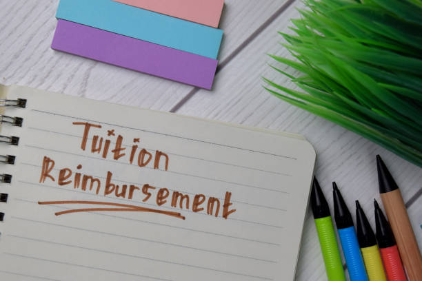 istock Tuition Reimbursement text write on a book isolated wooden table. 1279585421