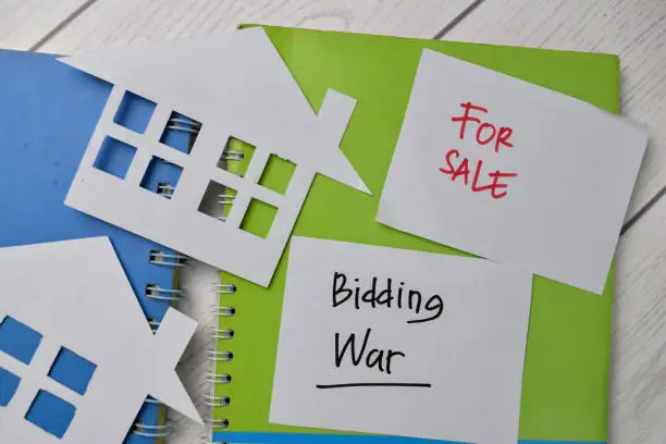 Photo of Bidding War and House For Sale write on sticky notes isolated on Office Desk