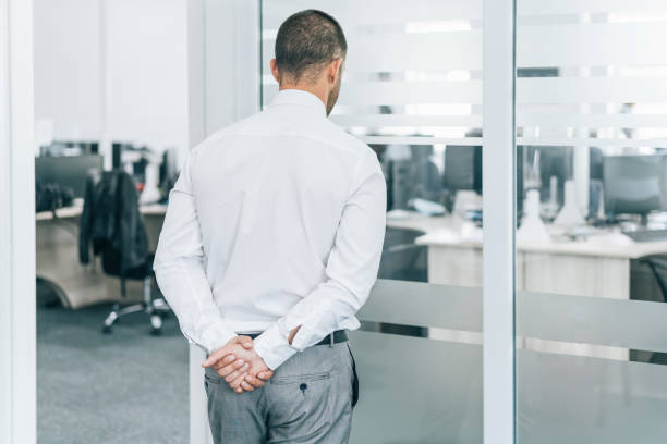 istock Worried businessman with his hands behind his back, watching the empty office,during COVID-19 1279598009
