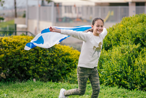 Happy Girl running with Israel flag. Image to illustrate election win, patriotic holiday Independence day Israel - Yom Ha'atzmaut concept.