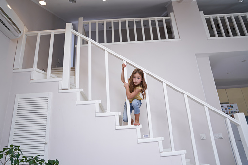 Little cute girl playing on stairs at home, happy childhood and children concept
