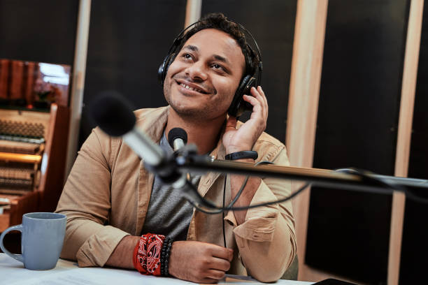istock Happy young male radio host looking aside while broadcasting in studio, using microphone and headphones 1279601643