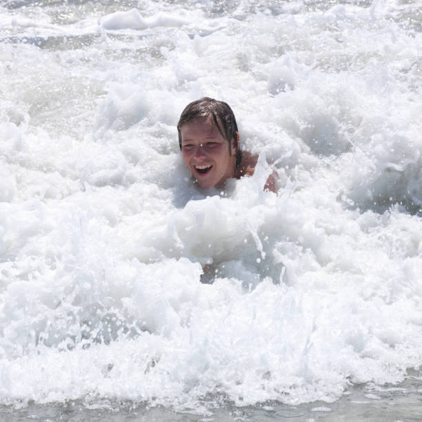 istock Teen boy plays in the surf 1279604469