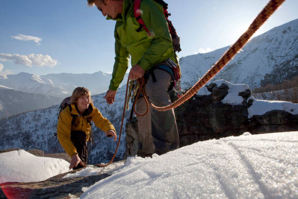 zobacz obok liny wspinaczkowej do ojca pomagającego synowi w zaśnieżonym grzbiecie górskim - on top of mountain peak success cold zdjęcia i obrazy z banku zdjęć