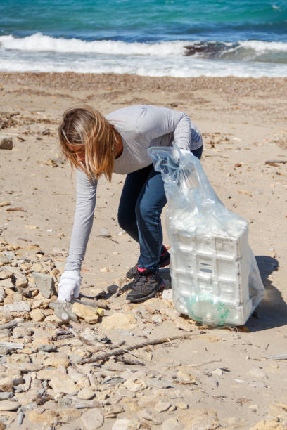 istock Young woman cleaning beach area from plastic 1279604855