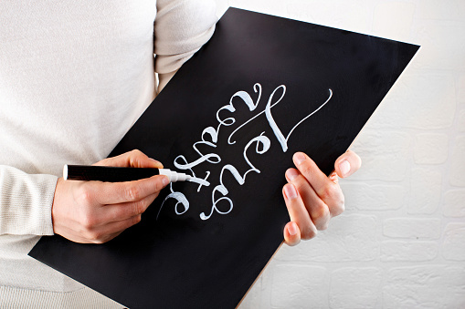 Woman writing on a small chalkboard zero waste lettering close up