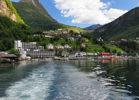 View From A Boat To Geiranger Village In The Geirangerfjord On A Sunny Summer Day With A Clear Blue Sky And A Few Clouds