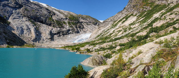 Panorama View From The Lake Nigardsbrevatnet To The Glacier Nigardsbreen In Jostedalsbreen National Park On A Sunny Summer Day With A Clear Blue Sky