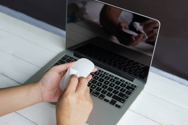 istock Man cleansing a computer mouse with antibacterial wet wipes for corona virus COVID-19 coronavirus prevention. 1279609460