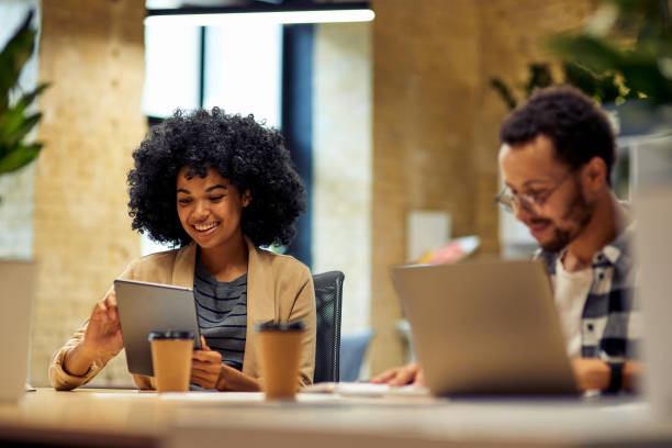 istock Two young happy multiracial business people sitting at the desk, using modern technologies while working together in coworking space 1279609707