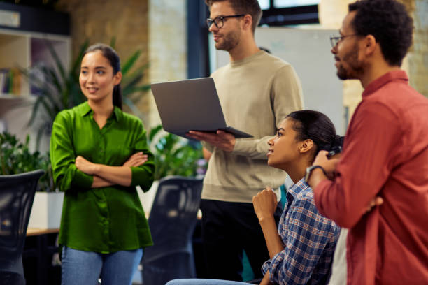 istock Group of young diverse multi ethnic business people using laptop and discussing project results while standing together in modern office 1279609773