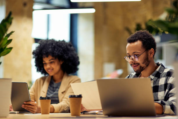 istock Using modern technologies. Two young multiracial business people sitting at the desk, working together in coworking space 1279609811