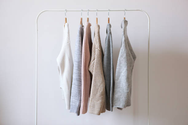 istock Warm sweaters on a wardrobe hanger on a colored background. Autumn, winter clothes. 1279611482