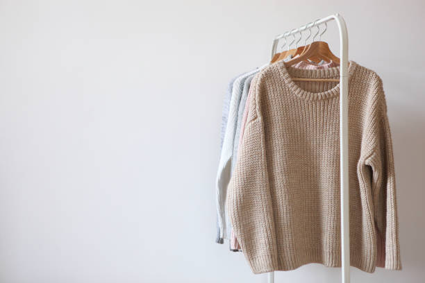 istock Warm sweaters on a wardrobe hanger on a colored background. Autumn, winter clothes. 1279611553