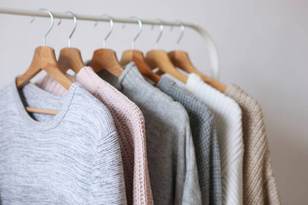 istock Warm sweaters on a wardrobe hanger on a colored background. Autumn, winter clothes. 1279611555