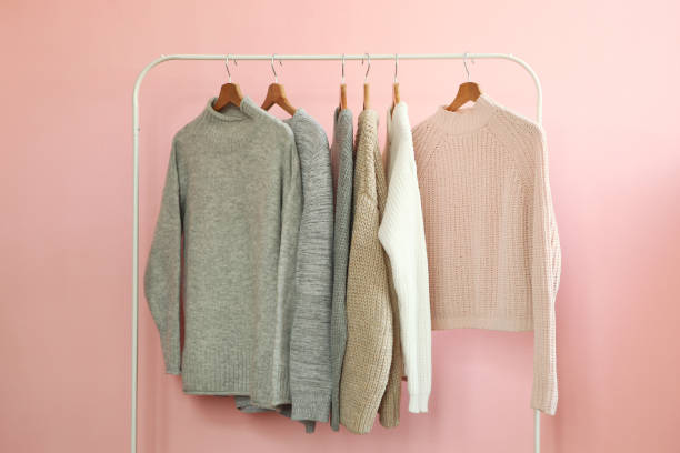 istock Warm sweaters on a wardrobe hanger on a colored background. Autumn, winter clothes. 1279612344
