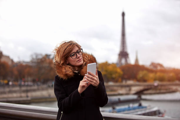 istock Girl using cellphone with Paris city background, Seine river and Eiffel tower. 1279613290