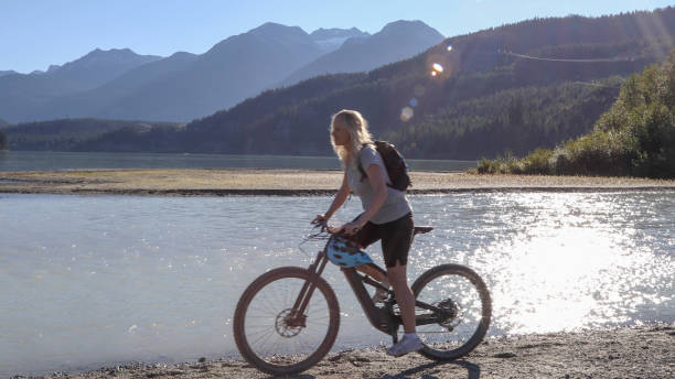 istock Female mountain e-biker rides along lakeshore 1279615391