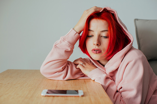 Portrait of a teen girl bored waiting for text message on smartphone device