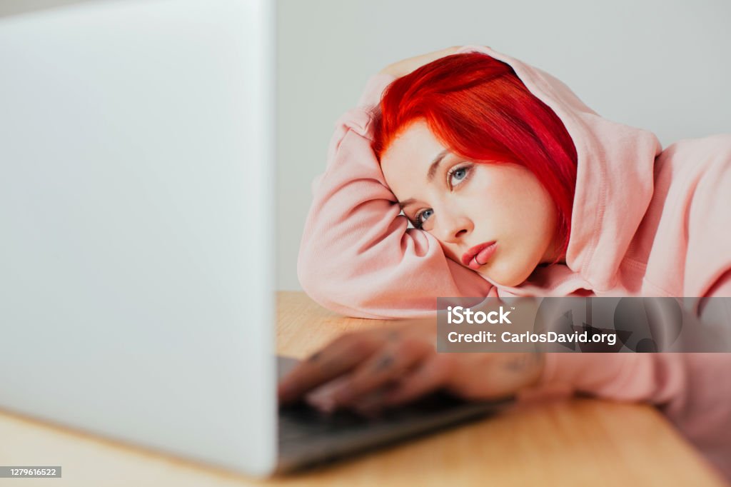 Portrait of a young woman  bored lying on desk using in laptop computer to surf internet Portrait of a teenager lying on desk using in laptop computer to surf internet Teenager Stock Photo