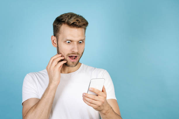 istock Shocked young guy looking on modern smartphone 1279617314
